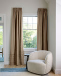 Coudre curtains in a living room with armchair